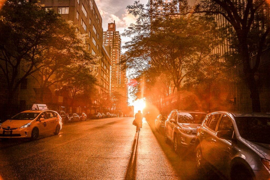 What to Look for When Choosing a Neighborhood in NYC 3 Sunrise on NYC street, man on a bicycle, buildings and trees